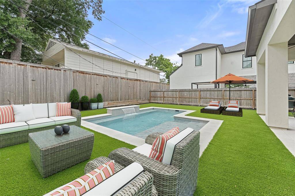 A serene scene in the backyard: a sparkling pool with sun shelf, and artificial turf all around. Note:Photo is virtually staged to show you the possibilities of this backyard! It's an outdoor oasis!