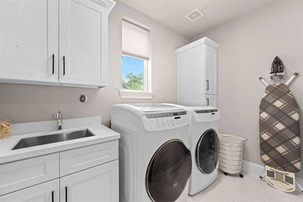 Upstairs, along with all the bedrooms, is the utility room. Built-in cabinetry flanks the washer and dryer. There is even an oversized stainless steel sink!