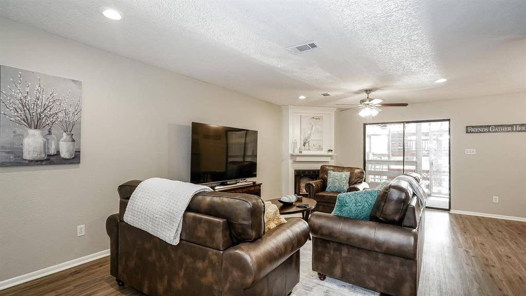 The living room has laminate wood floors, LED recessed lighting, a ceiling fan and freestanding fireplace.