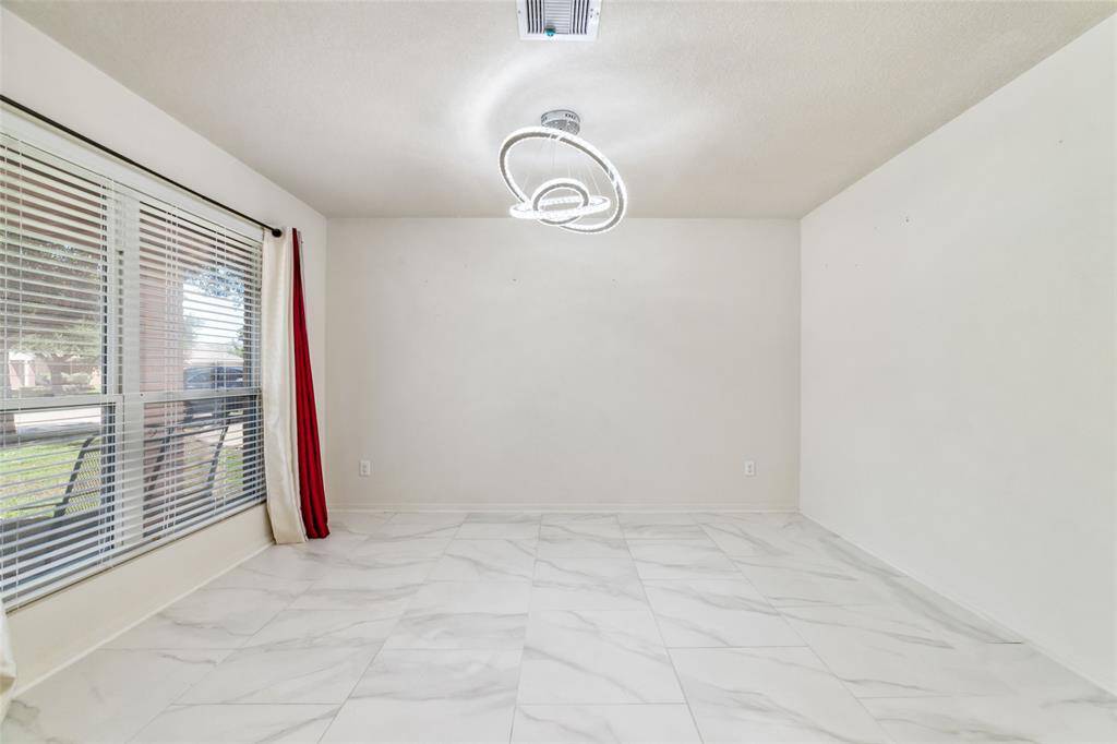 This is a bright room with large windows, modern light fixtures, and sleek white porcelain tile flooring.