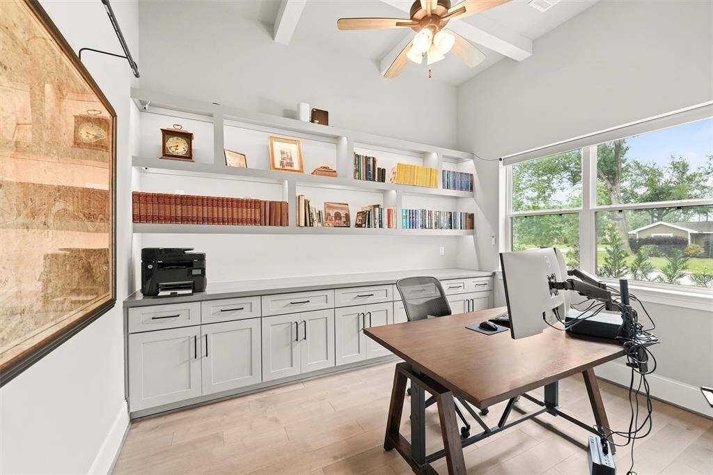 The study is equipped with built-in cabinetry and open shelving, and a modern beam ceiling detail.