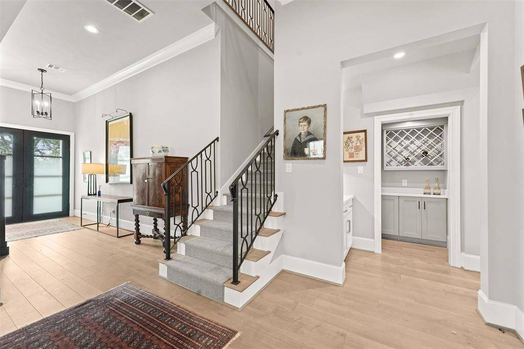 Between the front entry and the living areas is the staircase, with wool runner and wrought iron railing.