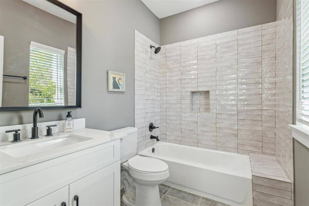 First-floor bathroom featuring quartz countertops and a trendy tile design in the tub/shower combo.