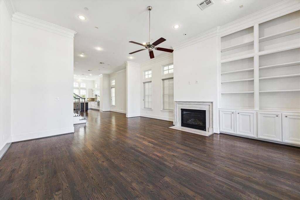 View of family room with display/book shelves and functional storage. The view is toward dining area and onto kitchen.