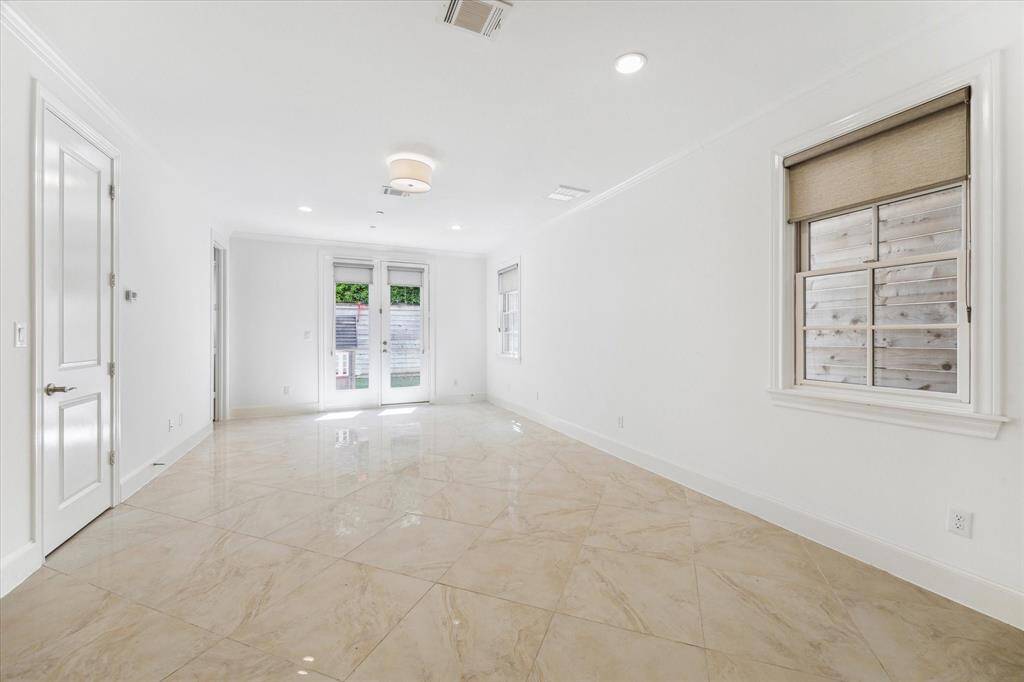 Full view of downstairs room off foyer toward double store front doors with access to private backyard.