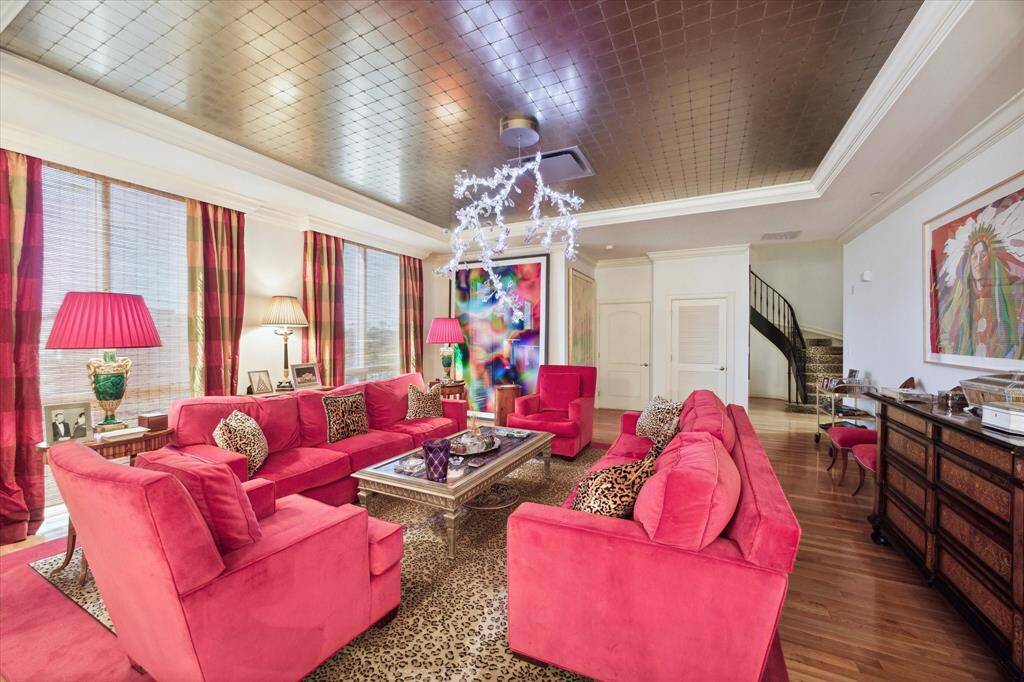 The formal living room and adjacent dining room has beautiful hard wood floors and windows overlooking Houston.