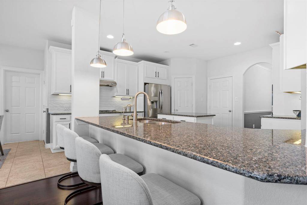 Stunning granite countertops elevate the gourmet kitchen, while the spacious breakfast bar wraps around with style and sophistication. Custom pendant lighting adds the perfect touch of elegance above!