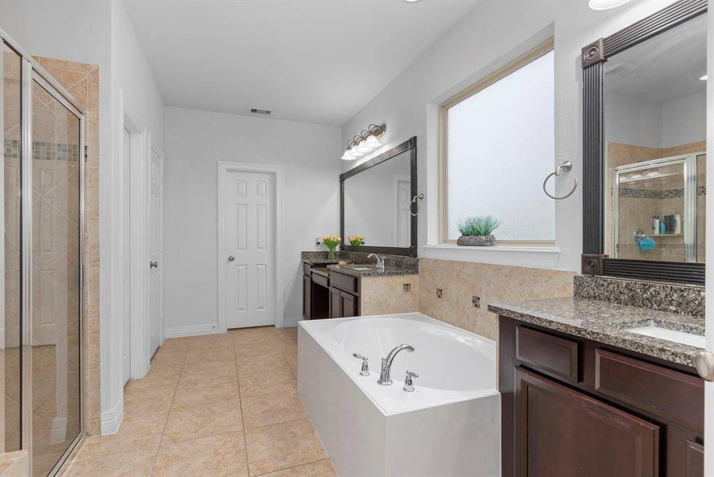 The Owner's Suite bathroom features his-and-her private vanities, framed mirrors for a custom touch, and wait until you see the massive walk-in closet—it's truly a standout!