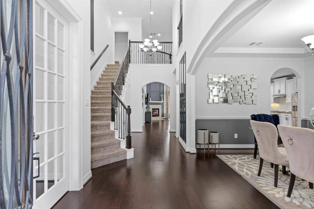 Be captivated by the stunning two-story entry, featuring gorgeous wood floors throughout! The sweeping iron staircase with balconies overlooks the first floor, while custom tall doors on the main level add a touch of dramatic elegance to this beautifully designed home!