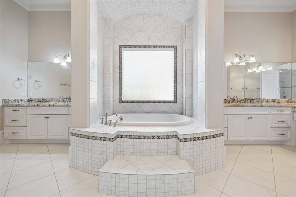 The primary bathroom features a spacious soaking tub, dual vanities with stone countertops, and lovely tile work.