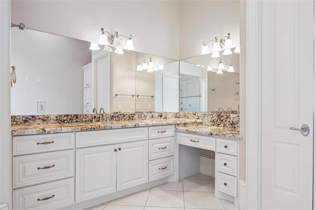 Luxurious bathroom featuring ample storage with white cabinetry, and bright, inviting lighting. Perfect for a serene and stylish retreat.