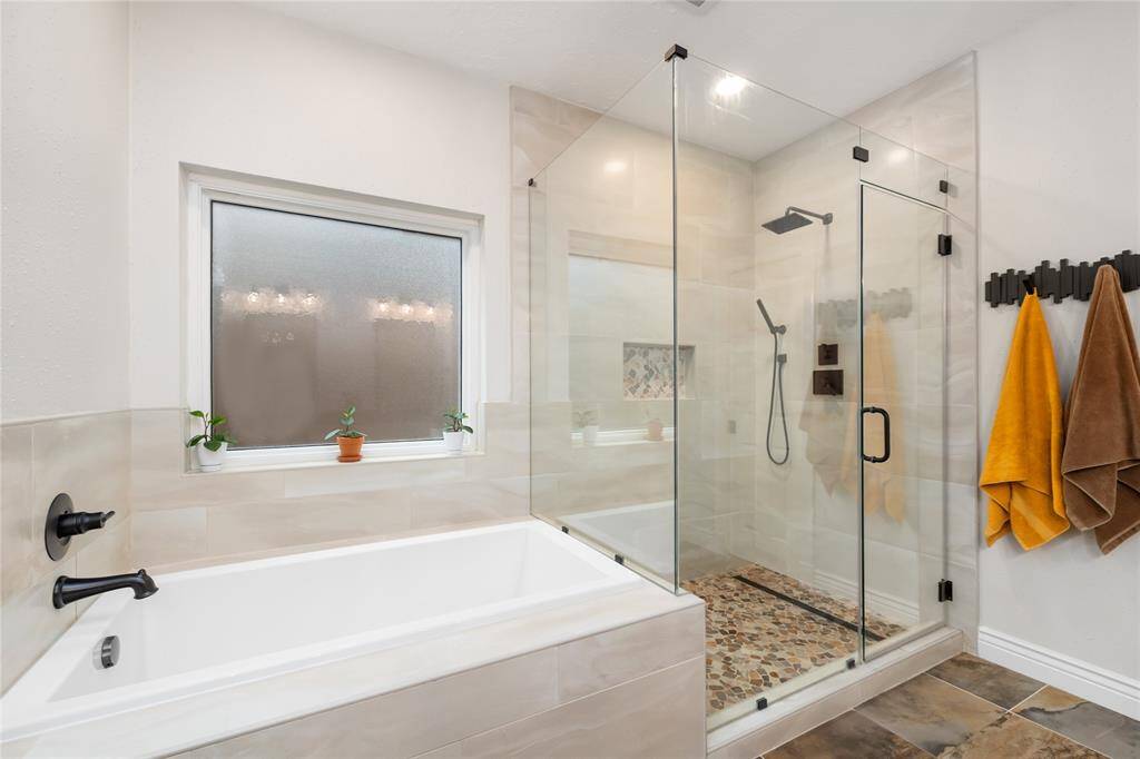 The frameless glass shower has multiple shower heads