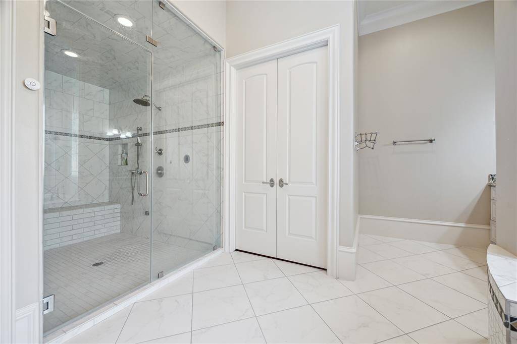 The bath also includes a spacious glass-enclosed steam shower with a built-in bench, tile floors, and modern fixtures.