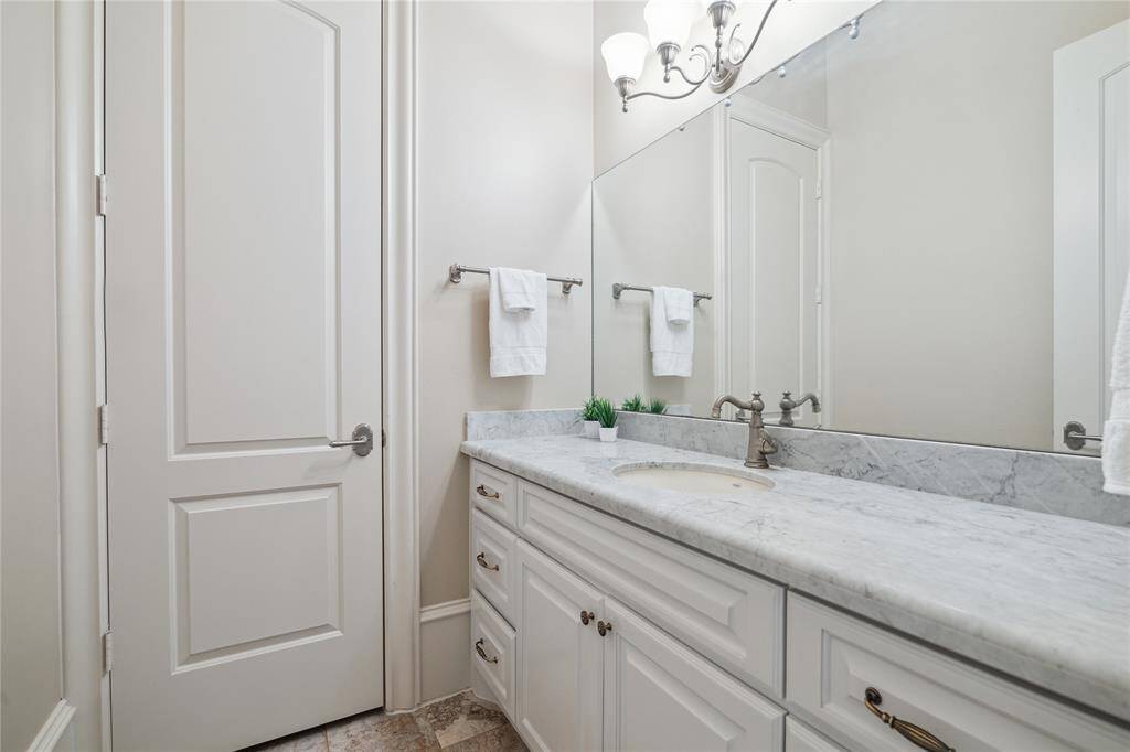 Elegant powder room featuring a marble countertop, ample cabinet storage, and a great design. Perfect for a touch of luxury in your daily routine.
