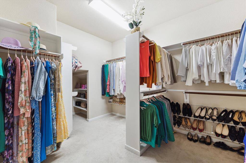 Spacious walk-in closet with ample shelving and hanging space, featuring organized sections for clothing and shoes.