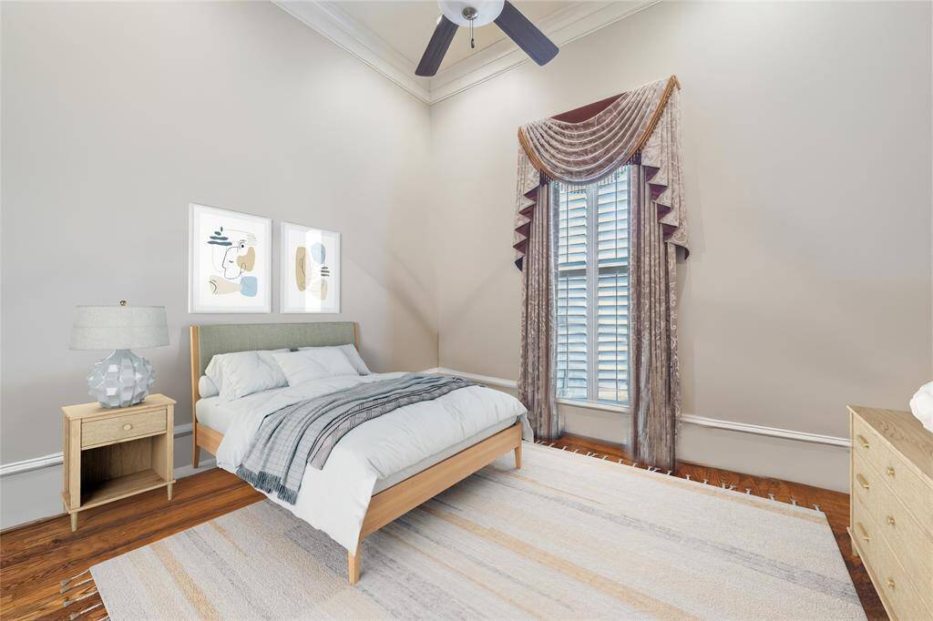 Inviting 2nd bedroom down featuring high ceiling, elegant crown molding, and warm hardwood floors. The large window with stylish drapery provides abundant natural light, creating a cozy and serene atmosphere.  (virtually staged)