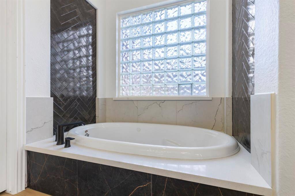 Indulge in luxury with a modern soaking tub and elegant tile accents.