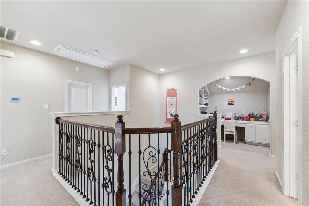 Second floor boasts 3 bedrooms , 2 full bath and a spacious gameroom. It features a decorative iron railing and an arched nook with a built-in desk, perfect for a study area. Recessed lighting adds a modern touch.