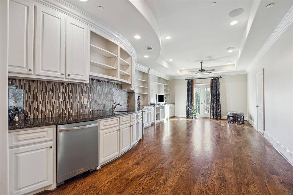 Sunlit game room featuring custom cabinetry, and a chic tiled backsplash. Perfect for entertaining, it boasts French doors that open to a serene outdoor view.