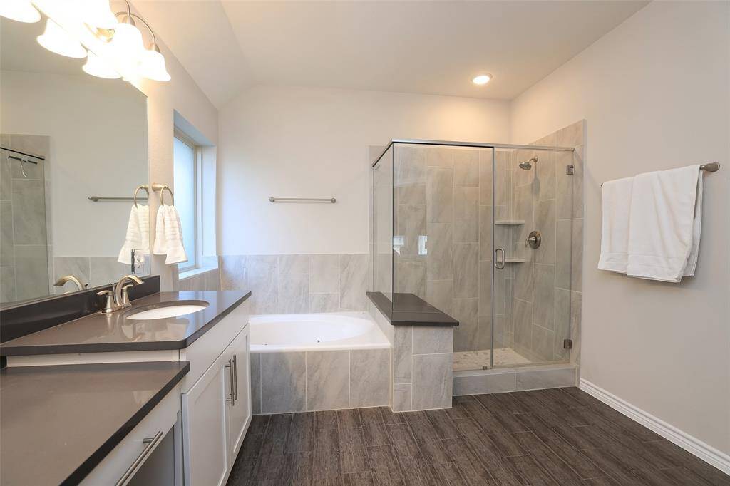 Well planned primary bath with deep gray quartz counters with vanity