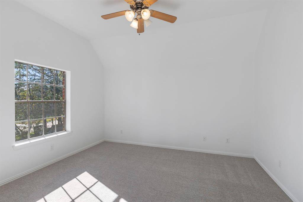 Bright and airy secondary upstairs bedroom with natural light and classic ceiling fan elegance.