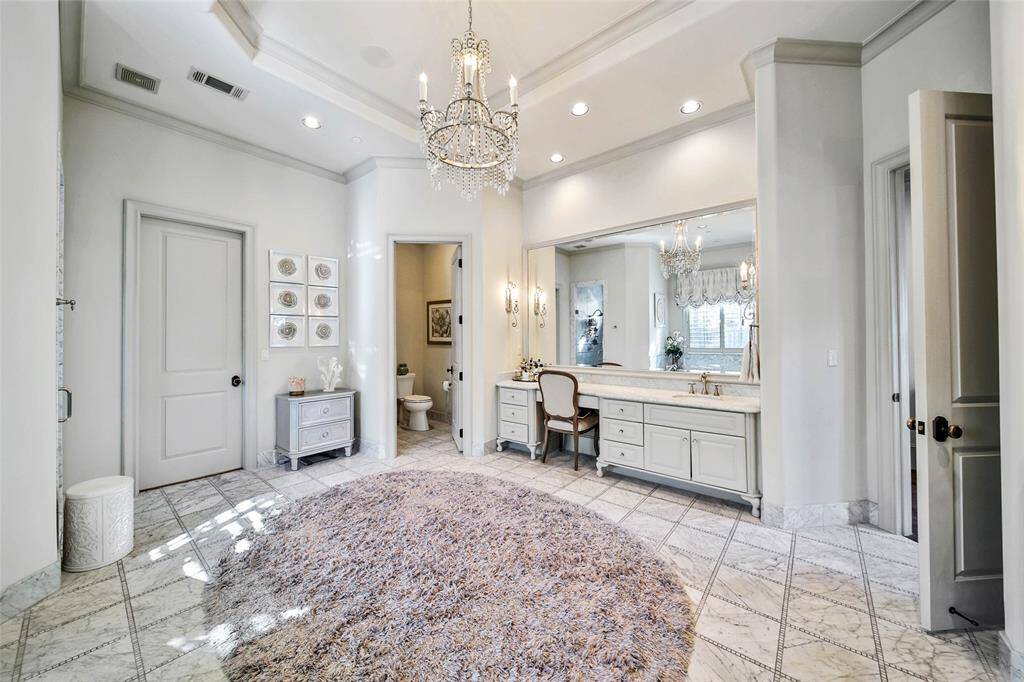 Stunning primary bathroom with double sinks, vanity area, his and hers closets, spa tub, and glass shower.