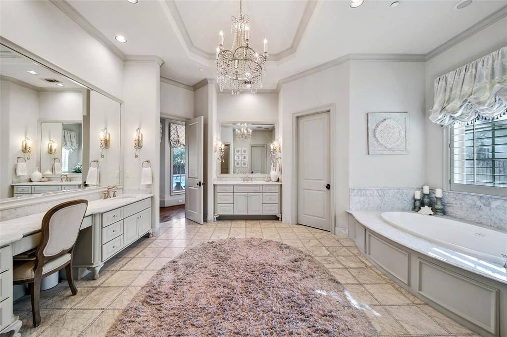 Stunning primary bathroom with double sinks, vanity area, his and hers closets, spa tub, and glass shower.