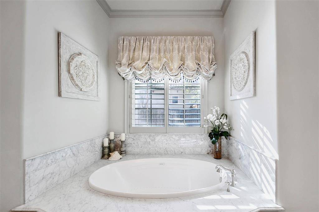 Stunning primary bathroom with double sinks, vanity area, his and hers closets, spa tub, and glass shower.