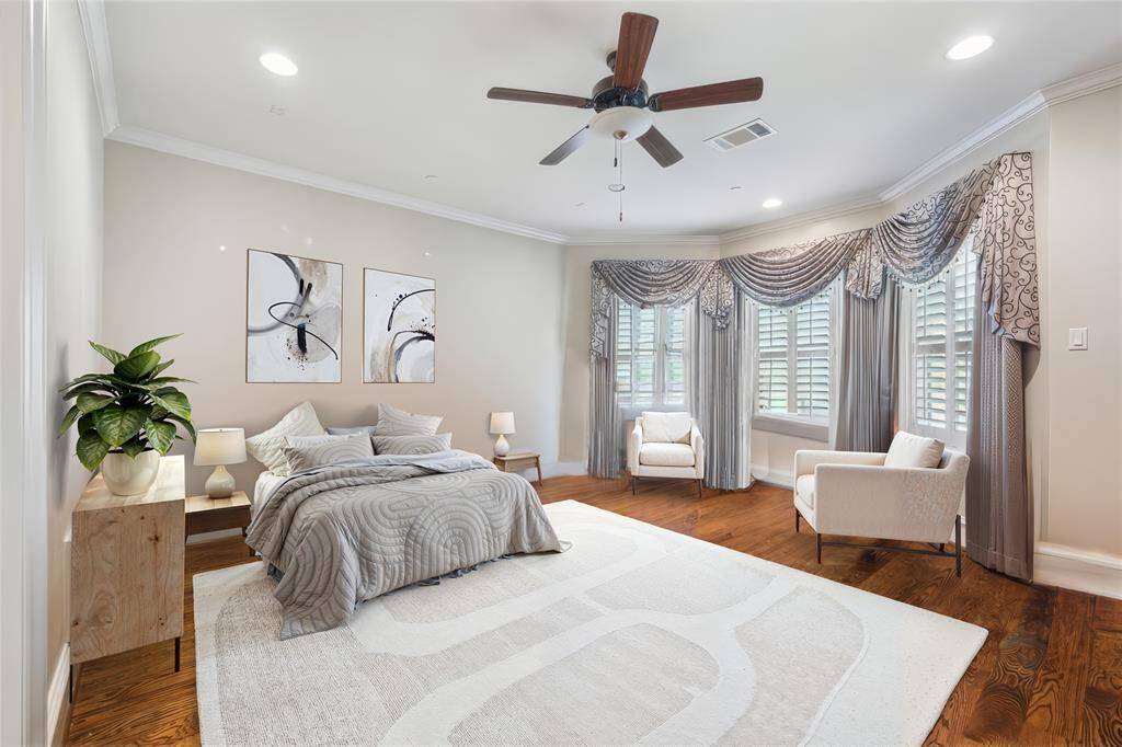 Spacious bedroom featuring hardwood floors, abundant natural light from large windows, and stylish décor.   (virtually staged)