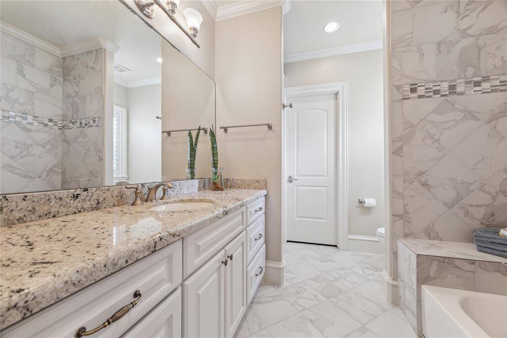 Bathroom featuring a stone vanity, sleek fixtures, and luxurious tile throughout.