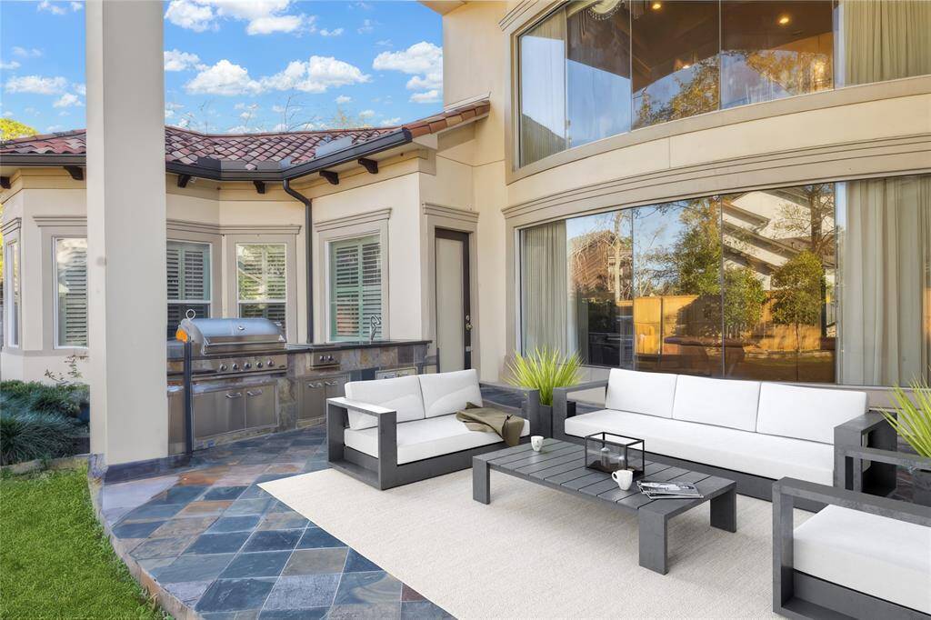 Outdoor living space featuring a summer kitchen, tile flooring, and comfortable seating. Perfect for entertaining and enjoying sunny days.  (virtually staged)