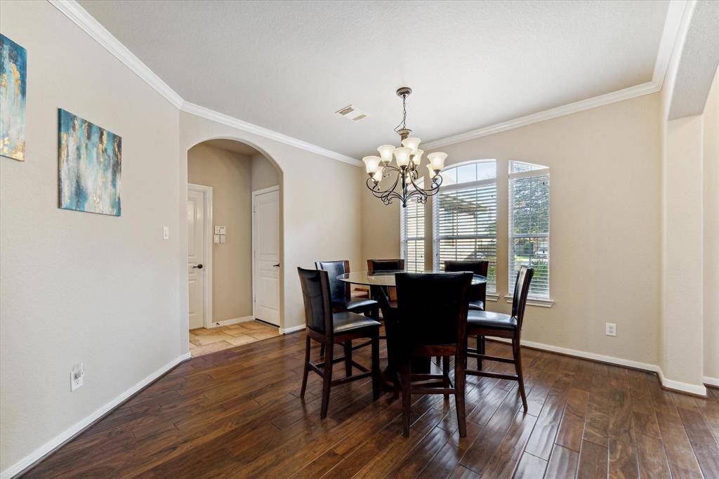 Bright dining room with hardwood floors and a stylish chandelier on the right of the entrance