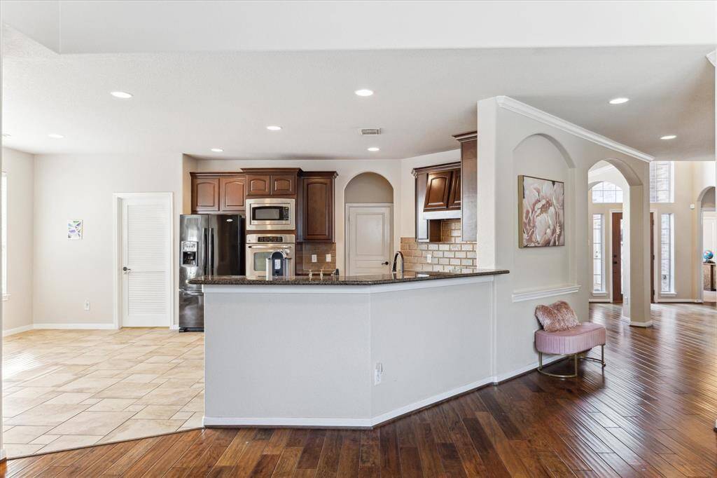 This inviting kitchen features a spacious open layout with a large island, stainless steel appliances, and warm wood cabinetry open to the Breakfast area.