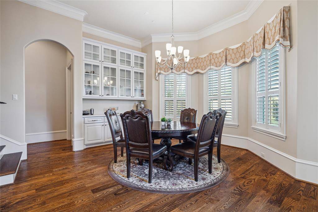 Breakfast room with hardwood floors, abundant natural light, and a charming chandelier. The built-in cabinetry offers ample storage, while the bay windows with plantation shutters create a cozy, inviting atmosphere.