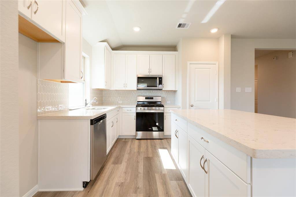 Escape and relax in the exquisite primary suite, a haven to unwind after a long day. The spacious room, located on first floor, boasts plush carpeting, soothing paint tones, high ceilings, and expansive windows adorned with privacy blinds. Sample photo of completed home with similar floor plan. Actual colors and selections may vary.