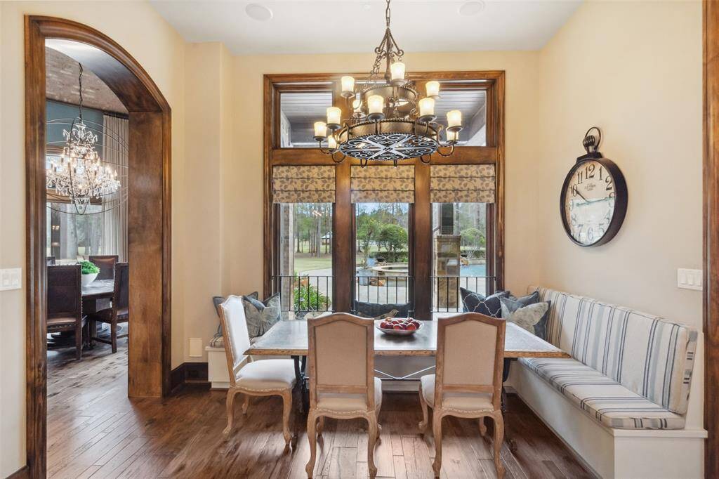 The gourmet kitchen features a generously sized breakfast area enveloped by a charming banquette with windows and transoms overlooking the sparkling pool and acreage beyond.