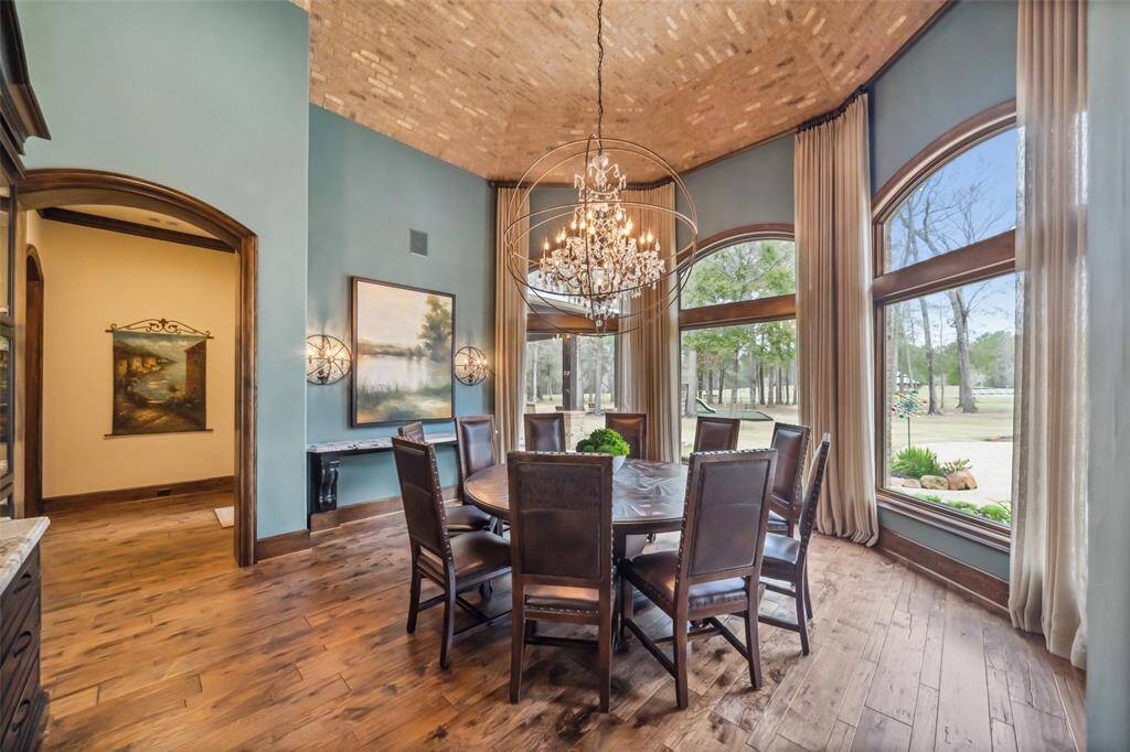 The formal dining room is surrounded by a bay of floor to ceiling windows and transoms affording views of the pool's sparkling water features, extensive property and pond.