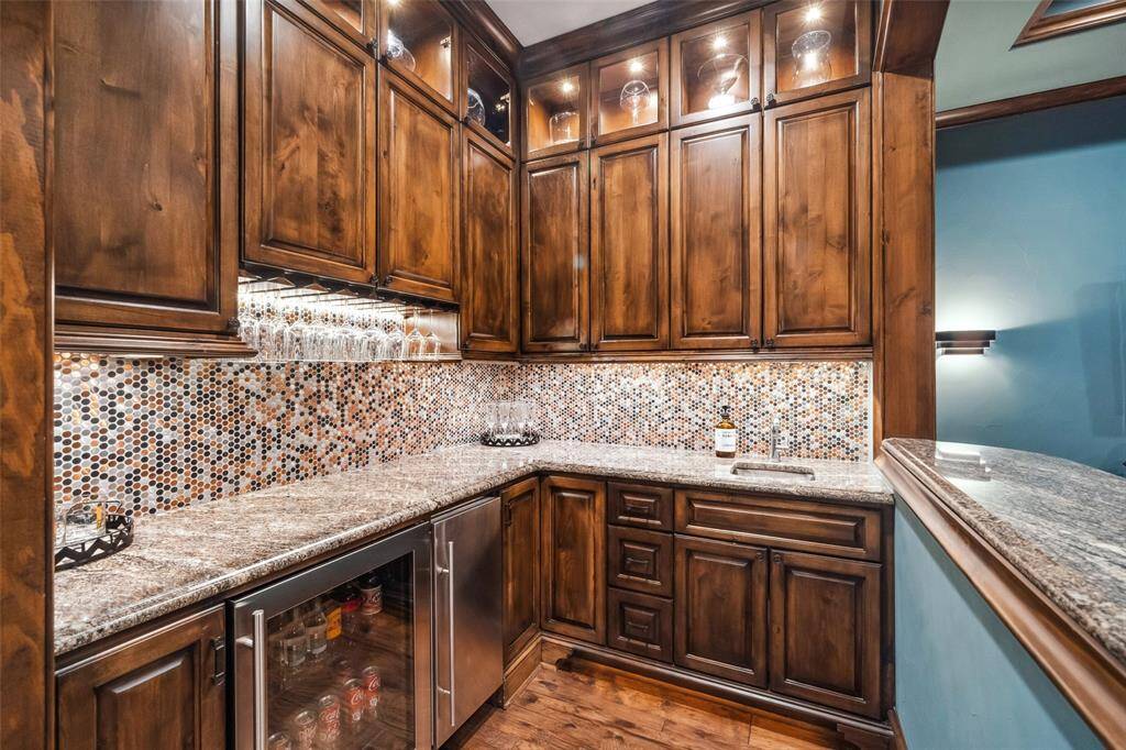 Abundant custom cabinetry with glass display cabinets above provides storage for all your glasses and barware. The beverage refrigerator, crushed ice machine and sink give the bartender their own domain at your celebrations.