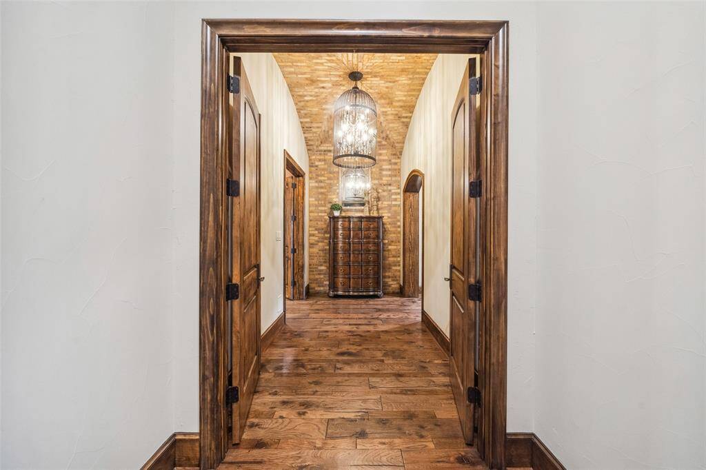 Tucked away from the rest of the home and accessed through double French doors, this charming vestibule leads to the primary bedroom suite. The passage is accented by meticulous brickwork from floor to ceiling and highlighted by an iron and crystal chandelier to set the mood.