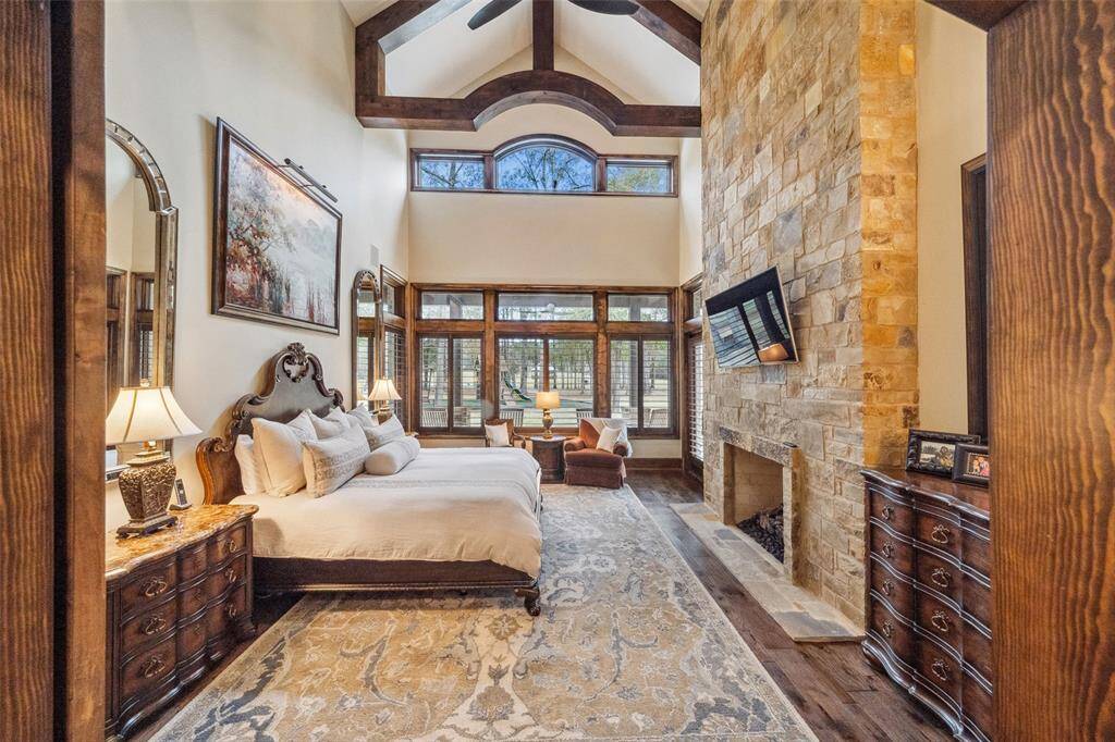 Wood beams add architectural interest and mimic the arched line of the transom windows soaring above. Wood plantation shutters adorn windows throughout the home and contribute to this private sanctuary.