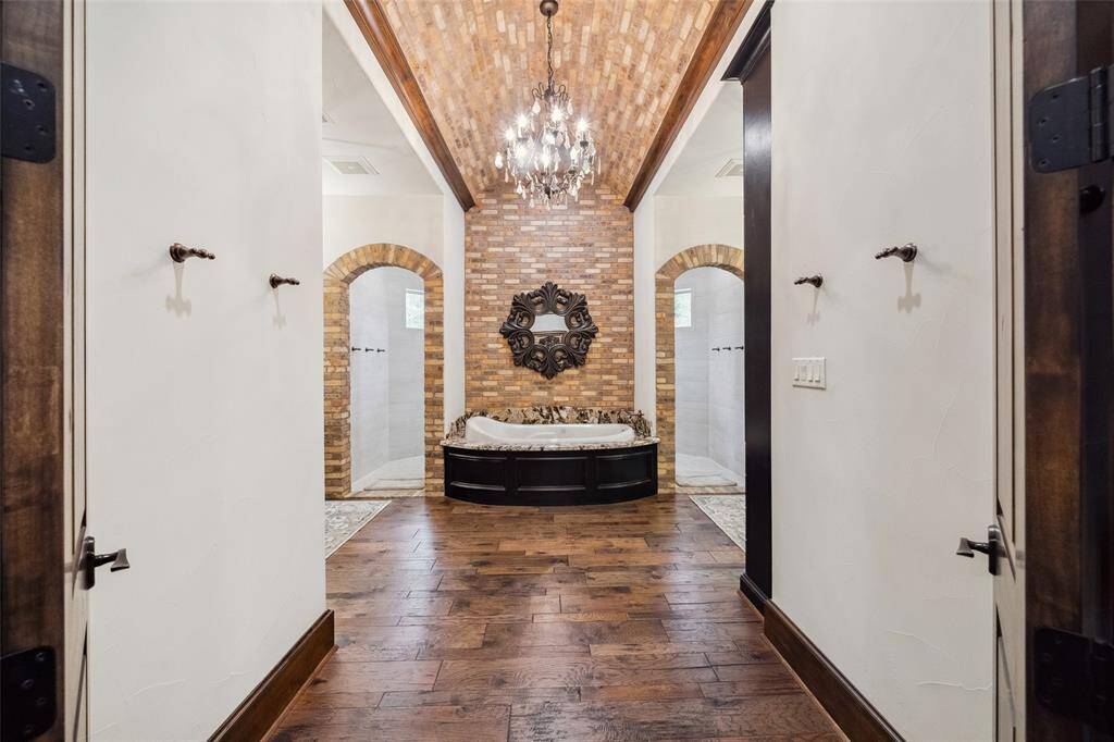 Pleasing symmetry in design is evident here. The soaking tub is strategically nestled between the dual shower entrances and highlighted by the masonry wall and ceiling, just beneath the crystal chandelier. The tub is an air jet tub which circulates no water but only air for more relaxing and hygenic experience.