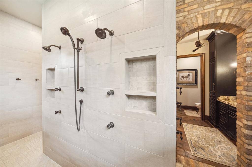 The walk through shower features multiple sprayers, dual shower heads and wand. Niches conveniently hold shampoos and potions. The shower's water flow may be engaged before entering as the controls are conveniently located just inside the brick archway. No need to step in until your water has reached the ideal temperature!