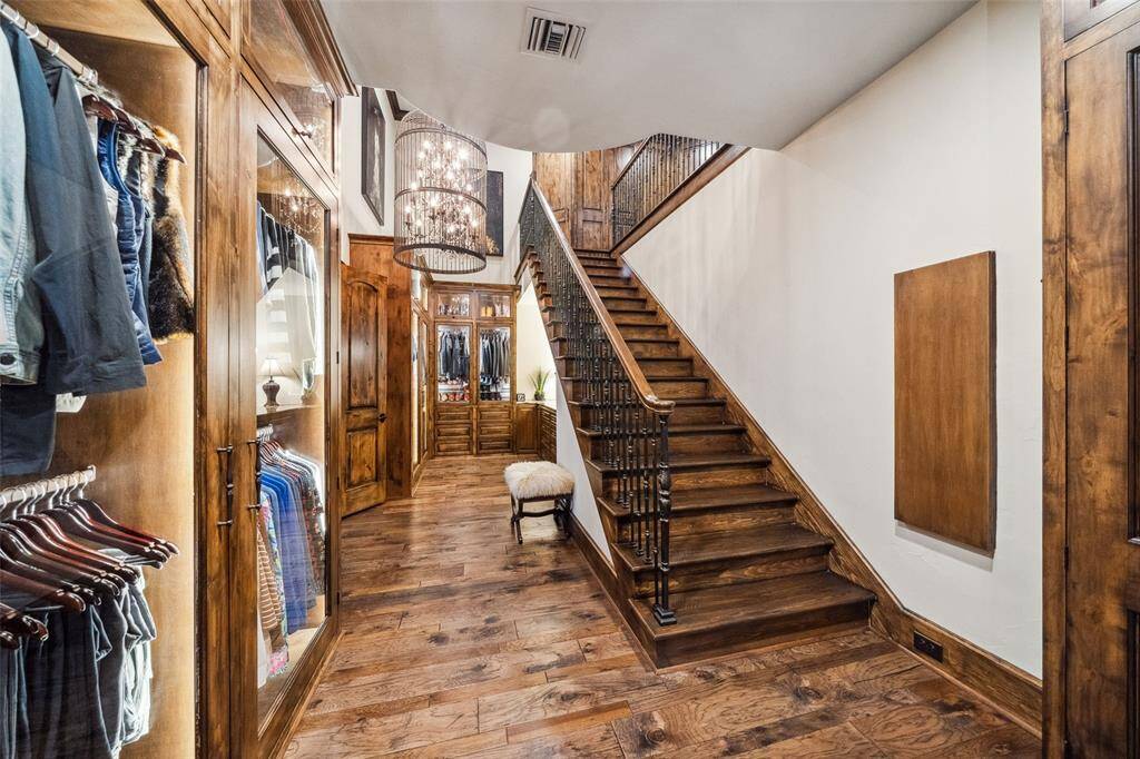 This two-story primary closet will spoil you! Custom built-in cabinetry with drawers, display cabinets and glass-front cabinets provide clothing storage that will keep your wardrobe organized and dust free! The stairs lead to the second level of the primary closet!
