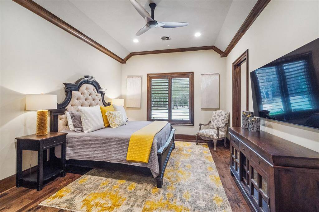 Just down a hallway that features a custom built-in book case to display family photos and mementos is another spacious secondary bedroom. Wood flooring flows throughout all bedroom suites.  The cove ceiling adds architectural interest. Wood plantation shutters adorn windows throughout the home.
