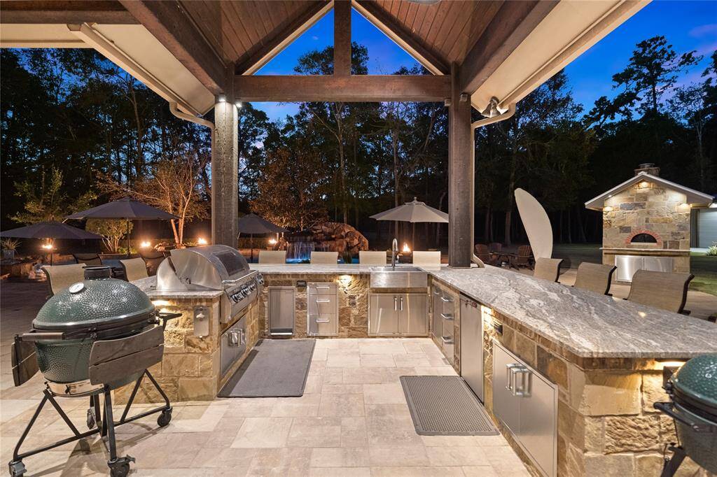 Below the soaring vaulted ceiling is the expansive outdoor kitchen featuring a propane gas grill, burner unit, multiple storage drawers, refrigerator, stainless steel apron front sink and beautiful granite countertops. Shaded from the hot Texas sun, enjoy entertaining and great company seated at the bar. Just steps away is the Valoriani Italian Wood-Burning Pizza Oven imported from Italy.
