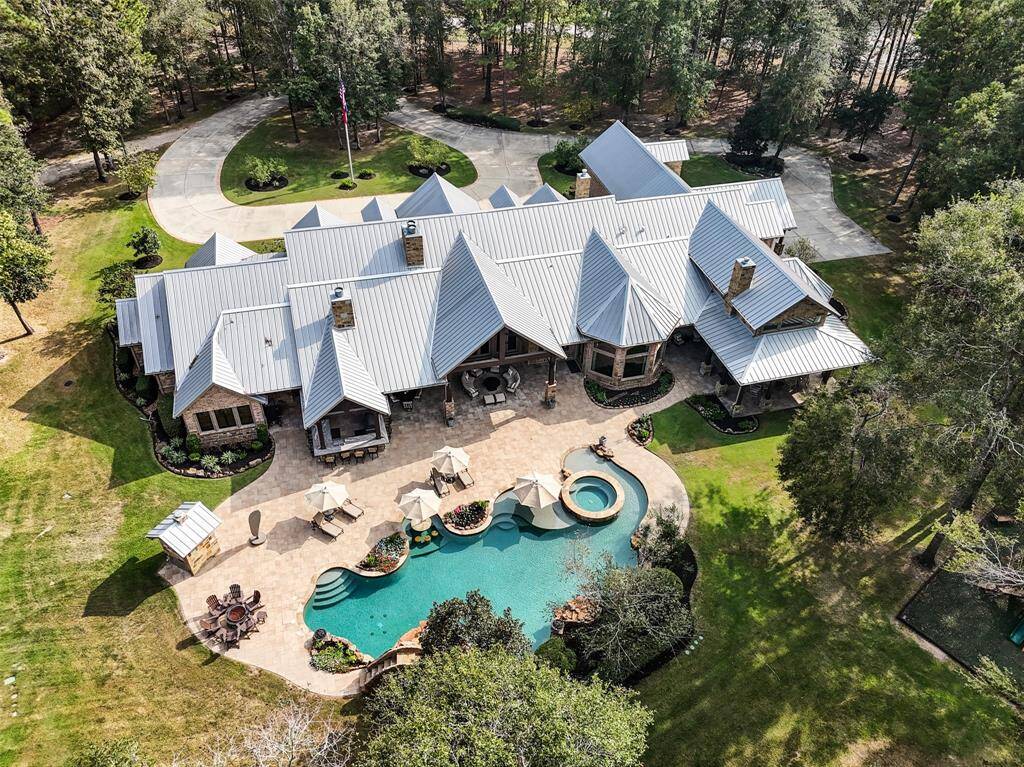 A tranquil oasis resembling a resort with ultimate privacy. The free form sport pool is a serene backdrop for entertaining. Flagstone coping, tile and Belgard pavers surround. The waterpark features convenient beach entry, hot tub, water features, waterfalls, slide, dining table and splash pad.