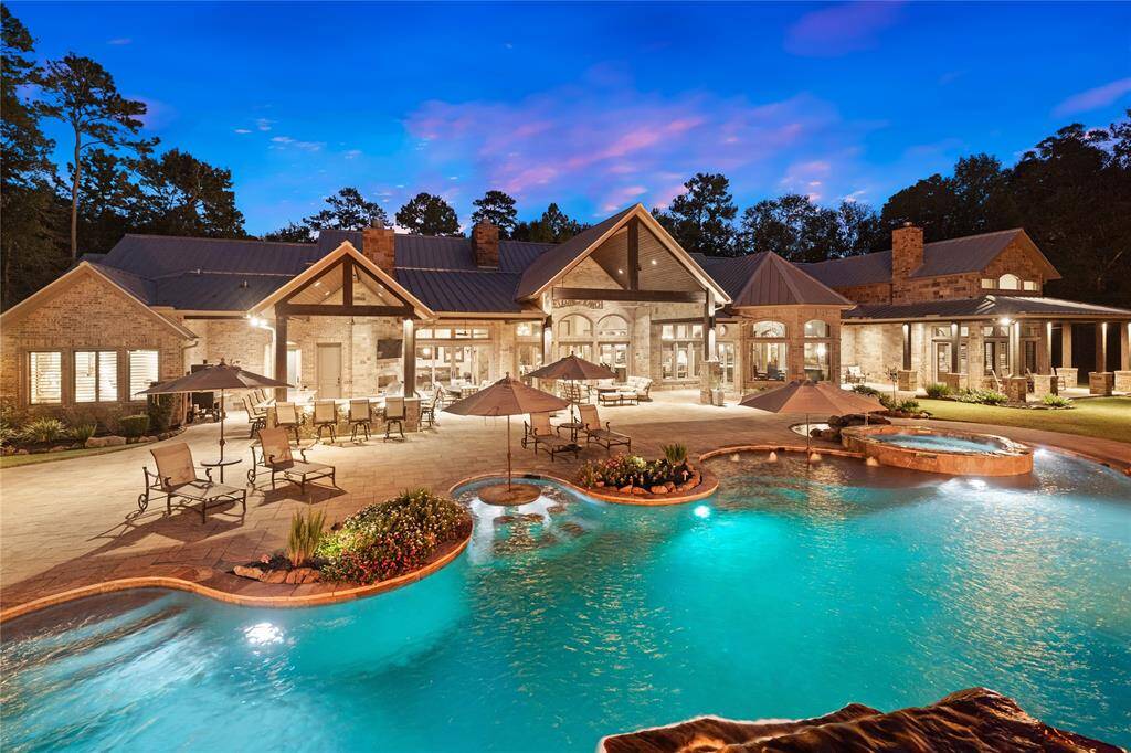 A rear view of the home at dusk shows the dramatic impact of the carefully planned lighting and waterpark design. Expertly placed lighting adds another dimension to this aquatic space, creating depth and drawing attention to the most impressive areas.