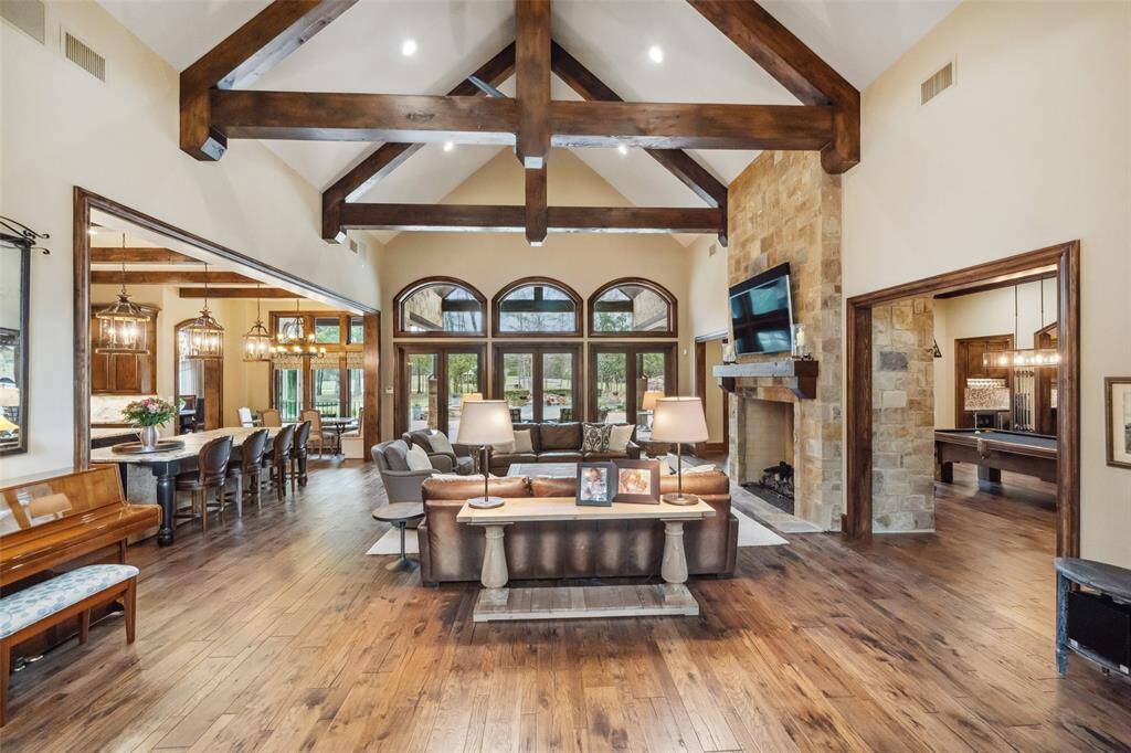 Upon entry, rich walnut hardwood flooring creates a uniform palette and flows toward the panoramic outdoor view of the surrounding estate. Your eyes are drawn up to the soaring cathedral ceiling adorned with handsome wood beams.