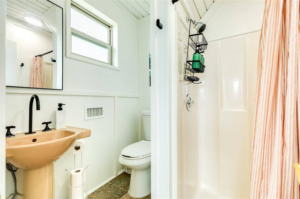 Charming bath featuring a sleek pedestal sink, modern fixtures, and a bright shower space. Ideal for a refreshing start to your day.