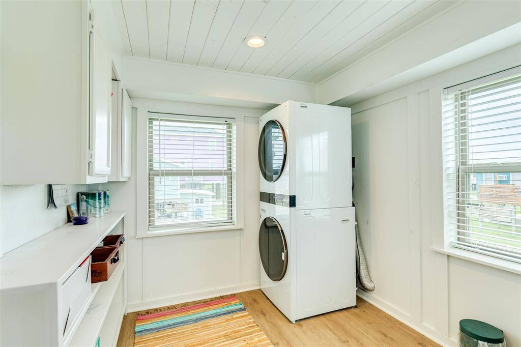 Bright and efficient utility room with ample storage and natural light, featuring modern stacked appliances.